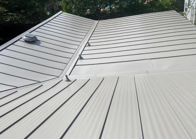 Solar attic fan installed on a metal roof for Roof Ventilation in Ira